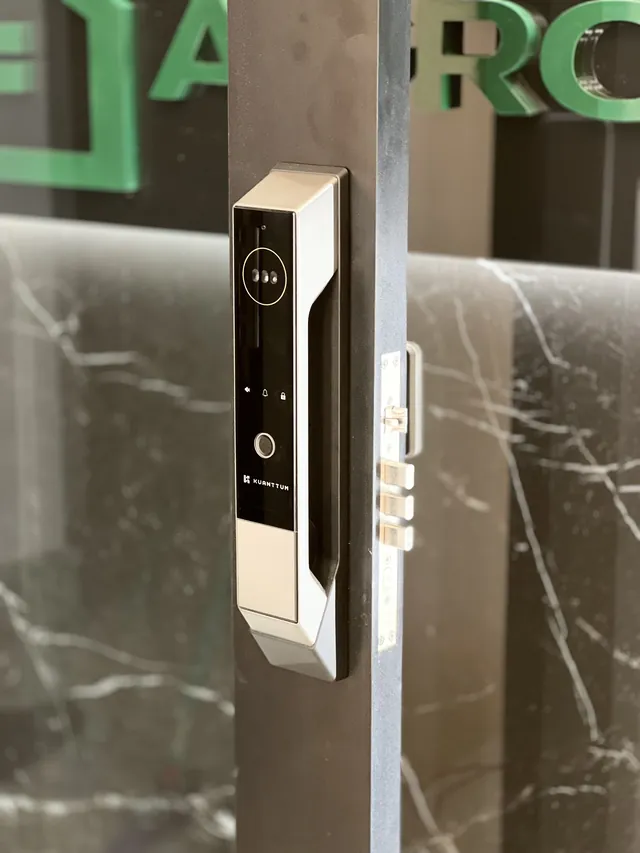 Fechadura digital dourada com leitor facial instalada em porta de mármore