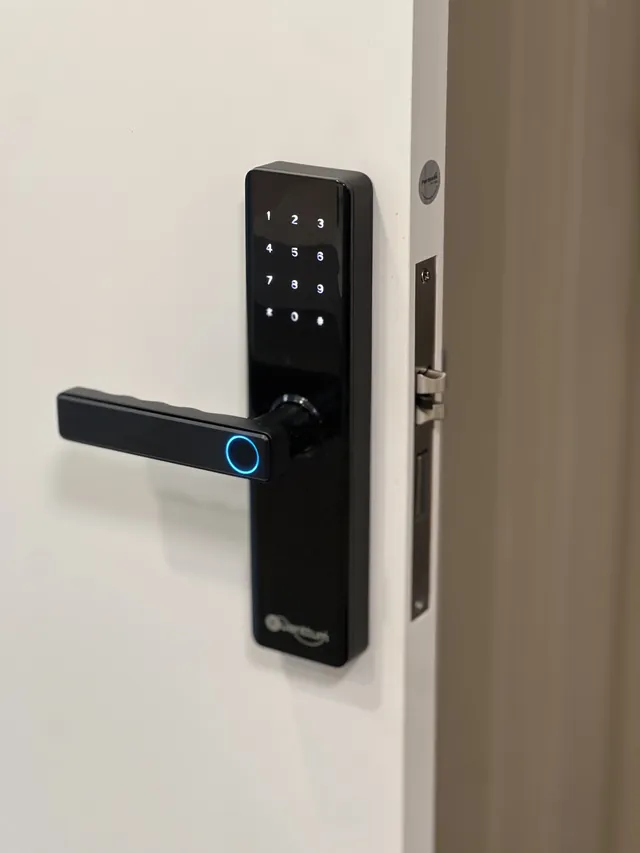 Fechadura digital preta com teclado e leitor biométrico instalada em porta branca