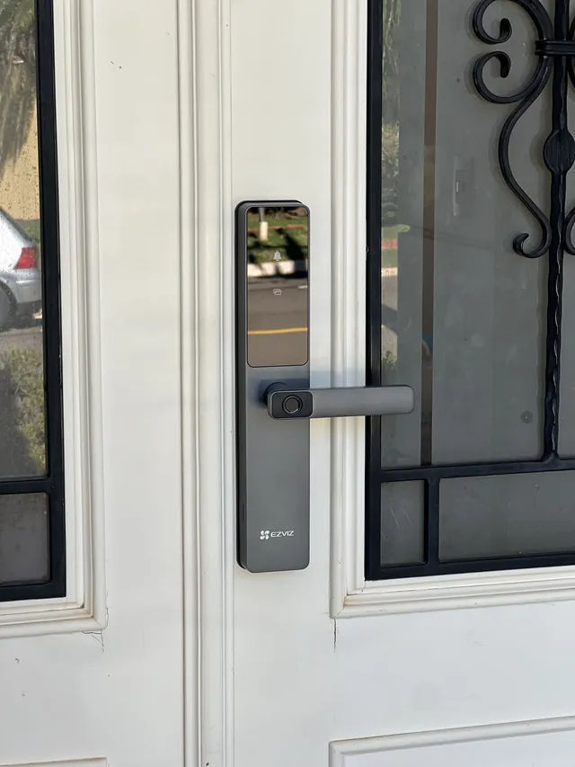 Fechadura digital Ezviz instalada em porta de vidro com grade